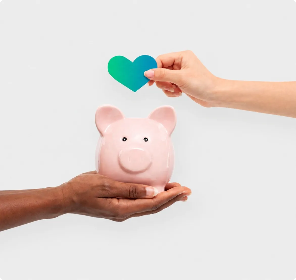 Una mano entrega un corazón sobre una alcancía con forma de cerdito